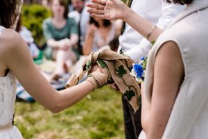 Hands bound with a handfasting cord made from hessian and crocheted ivy leaves