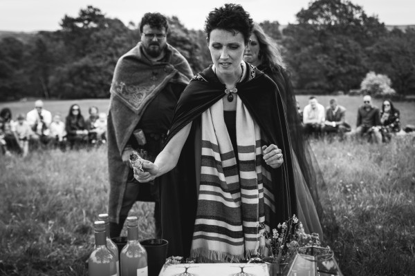 Pagan Celebrant Keli Tomlin uses a sage bundle to smudge the wedding altar while the bride and groom stand behind and watch