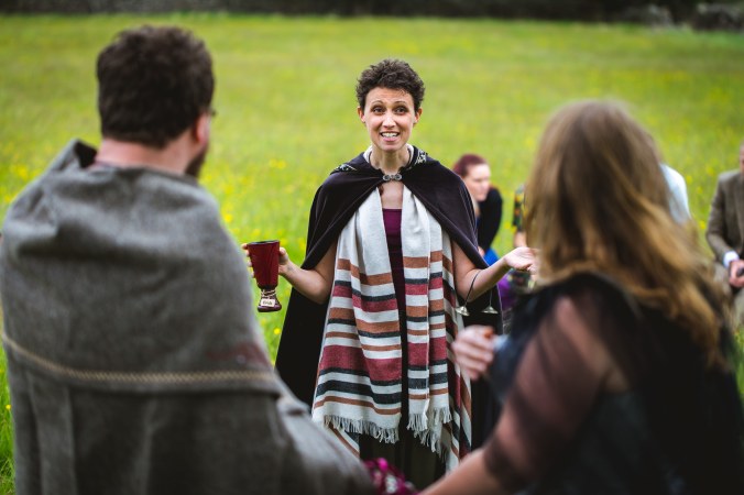 A Celebrant smiles at the bride and groom during the cake and wine ritual of a pagan viking wedding in Grindleford by Keli Tomlin Ceremonies