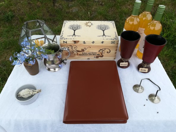 An altar set for a Viing Pagan Wedding by Celebrant Keli Tomlin including sacred bells, cups, mead, candles, forget-me-nots, sage smudge and a decorative wooden box.