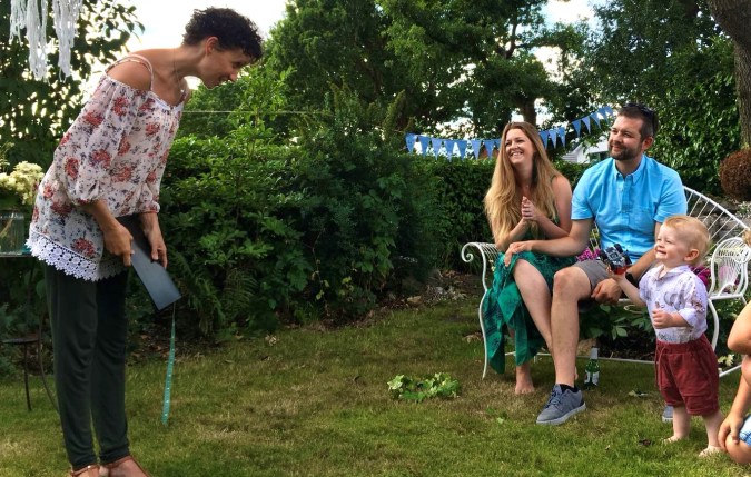 A small child smiles up at an adult who is bending to speak to him during his Naming Day Ceremony by Keli Tomlin Ceremonies